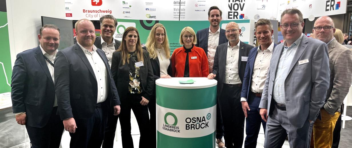 Personengruppe auf einem Messestand schaut in die Kamera.