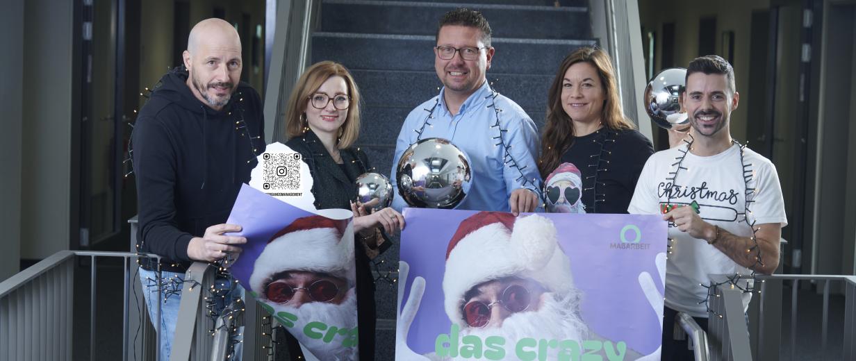 Fünf Personen mit Weihnachtsschmuck stehen in einem Treppenhaus.