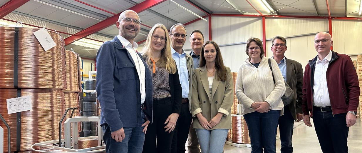 Eine Personengruppe steht in einer Lagerhalle.