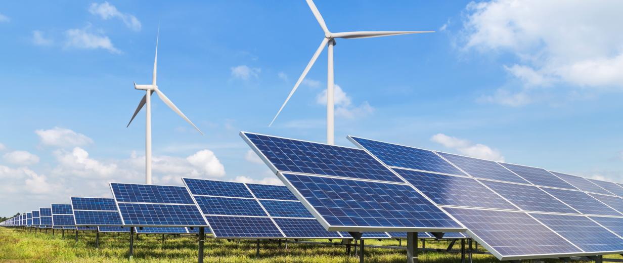 Photovoltaik-Anlagen und Windkraftanlagen stehen auf einer Wiese