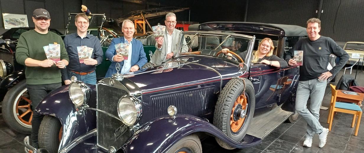 Sechs Personen stehen hinter und vor einem Oldtimer.