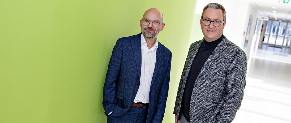 Zwei Personen stehen in einem Gebäudeflur.