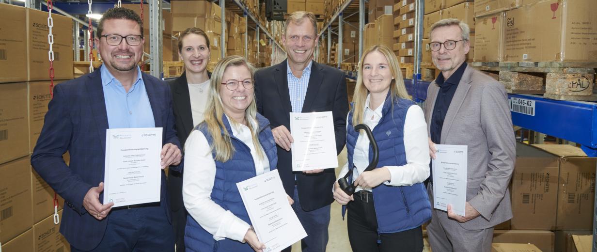 Sechs Personen stehen in einem Hochregallager.