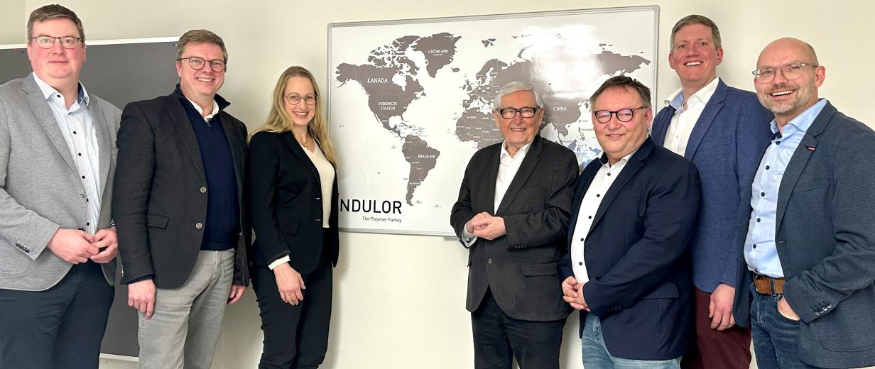 Sieben Personen stehen vor einer Weltkarte.