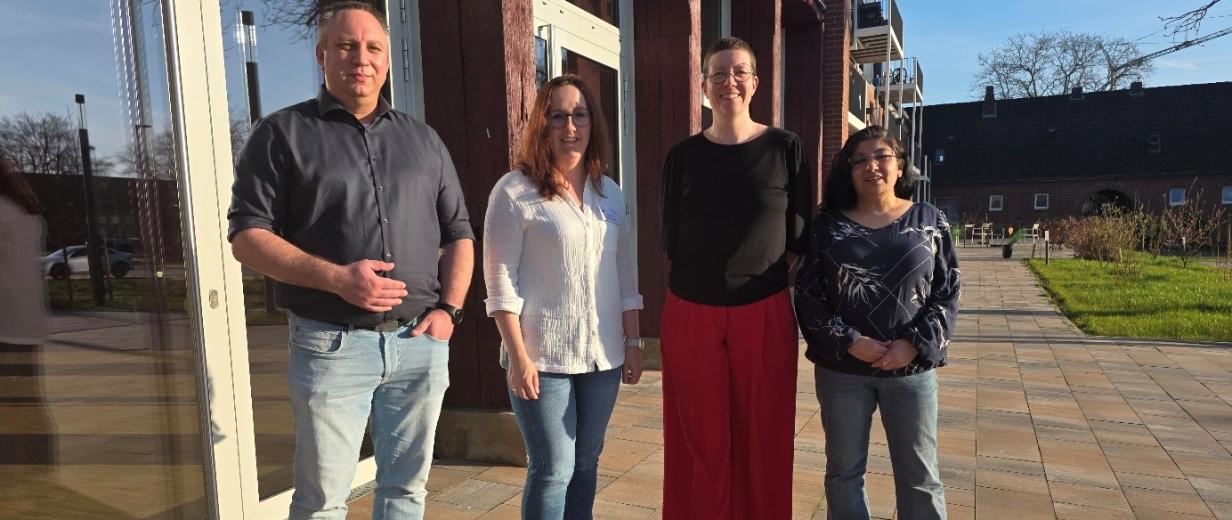 Vier Personen stehen vor einem Gebäude.
