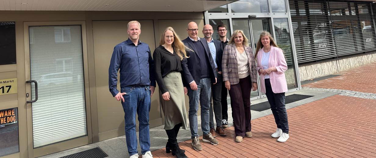 Gruppe von Personen vor Haus stehend