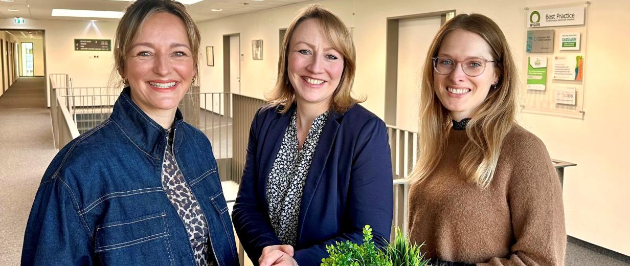 Drei Personen an einem Stehtisch in einem Bürogebäudeflur