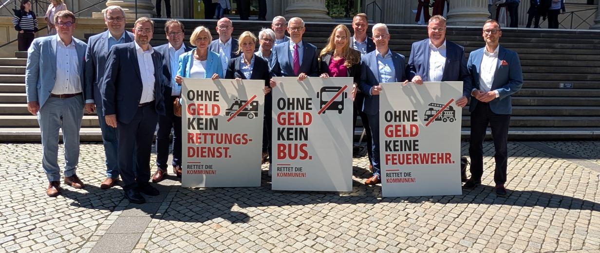 Personengruppe mit Plakaten vor einem Gebäude mit Säulenportal