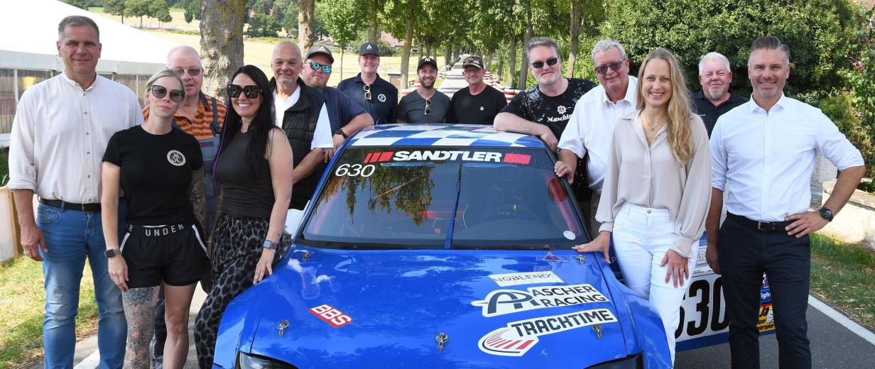 Gruppe von Personen stehend um Sportwagen