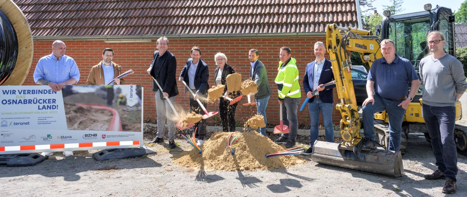 Eine Peronengruppe mit Schaufeln steht hinter einem Sandhaufen.