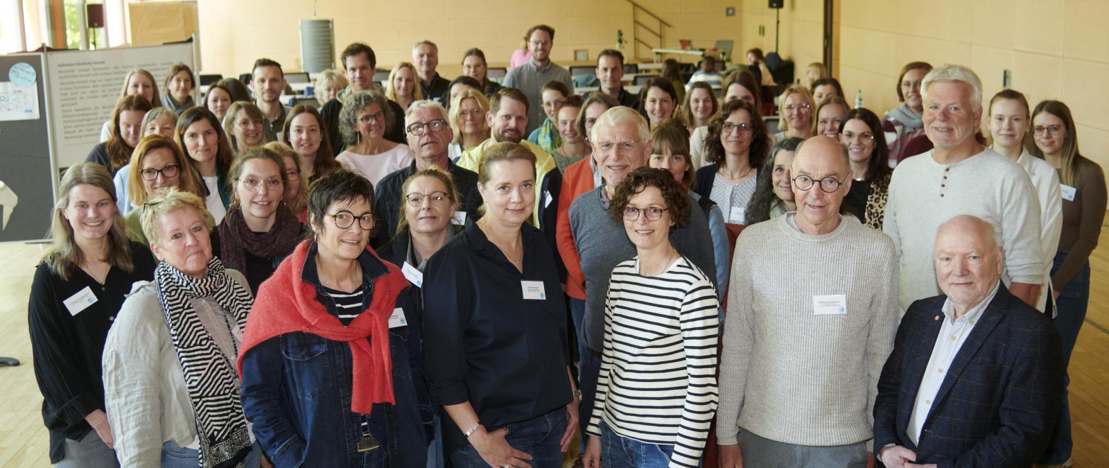 Eine Personengruppe steht in einem Versammlungssaal.