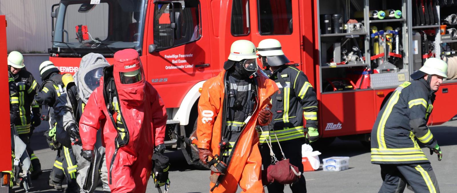 Personen in Schutzkleidung vor einem Feuerwehrfahrzeug