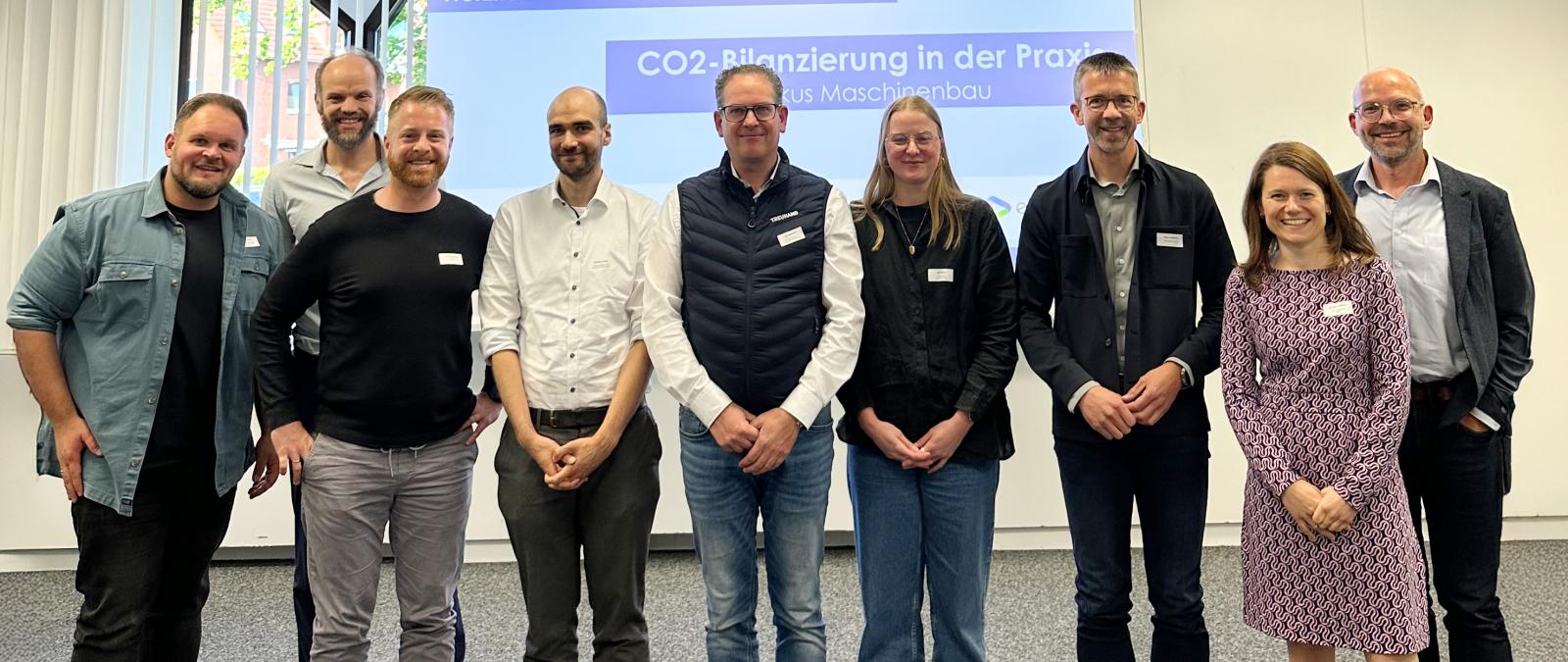 Eine Personengruppe steht vor einer Projektionsfläche.