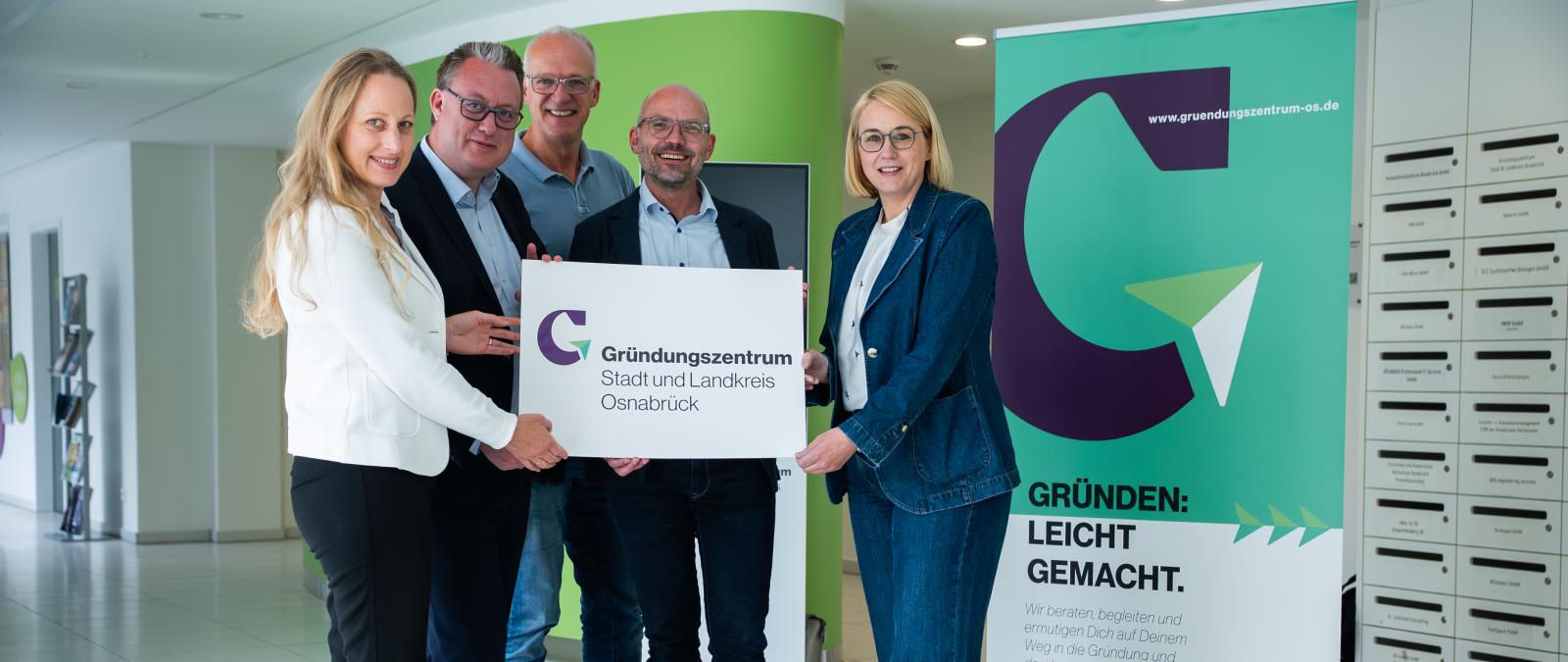 Fünf Personen stehen im Foyer eines Gebäudes.
