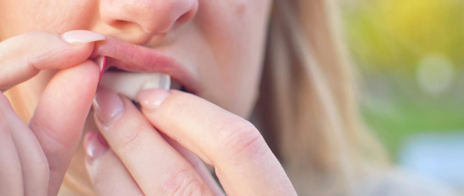 Frau schiebt sich Nicotine Pouches unter die Lippe