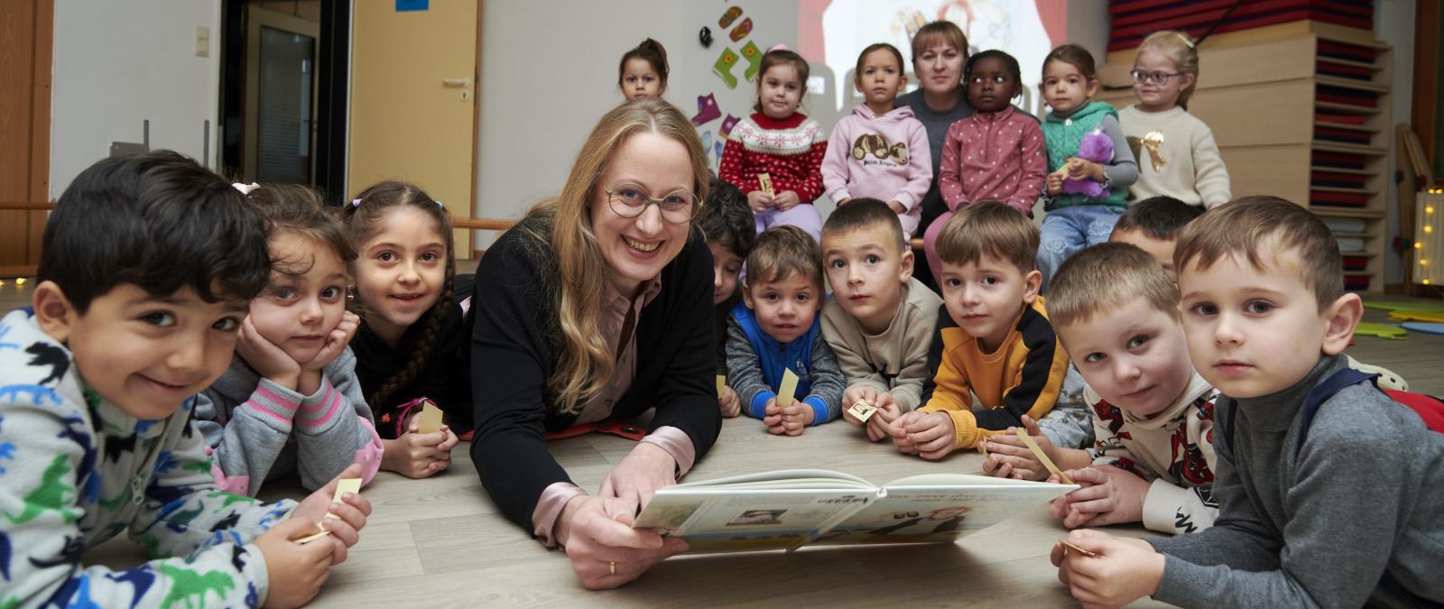 Eine Personengruppe liegt auf dem Boden eines Raumes und schaut in die Kamera.