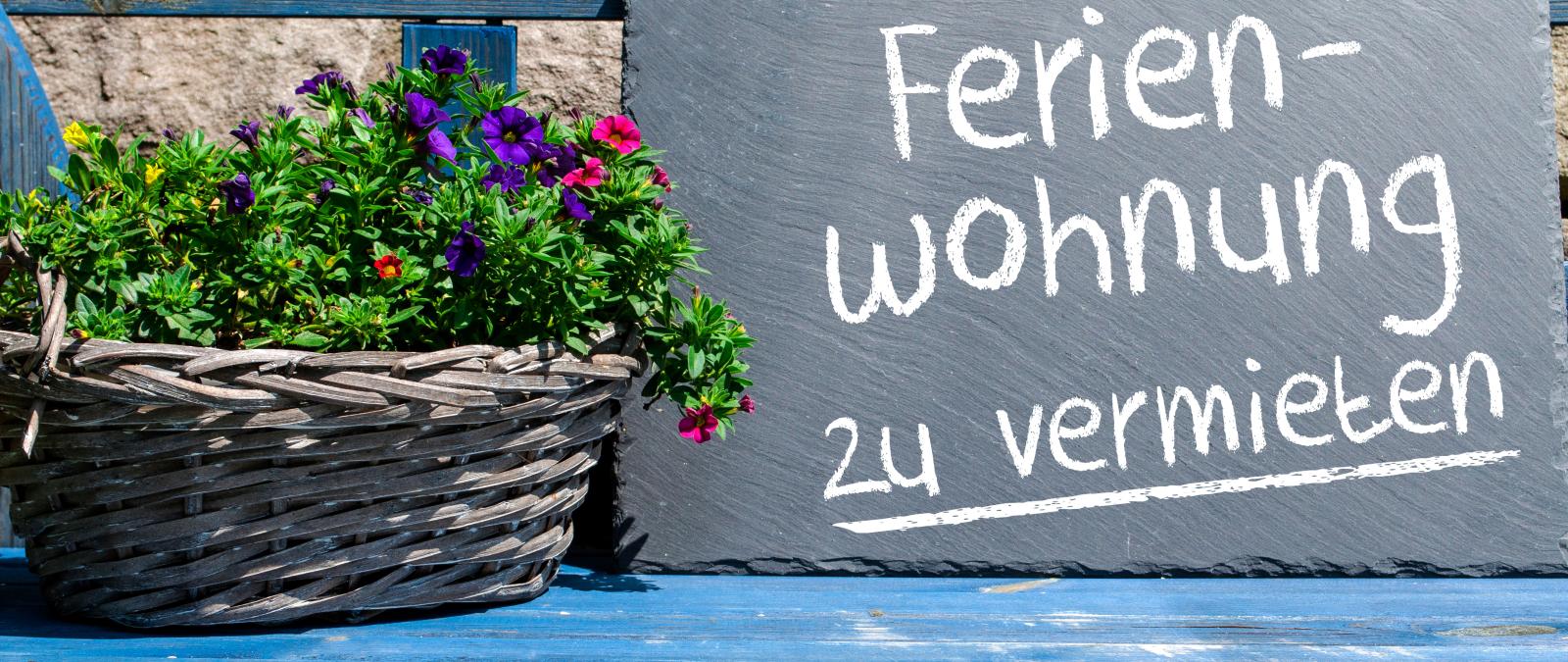 Schild steht auf einer Bank mit der Aufschrift Ferienwohnung zu vermieten.