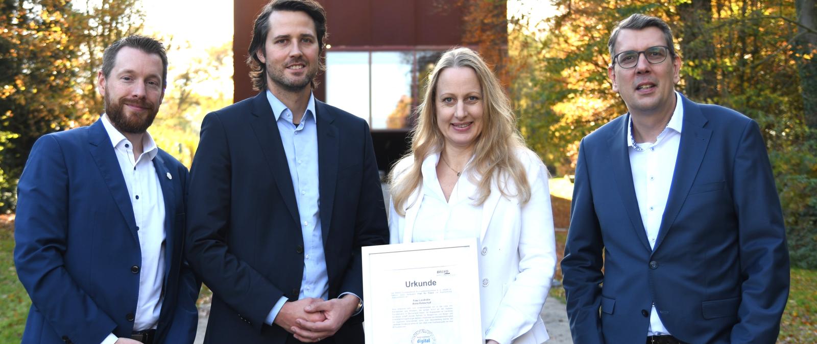 Vier Personen stehen in einem Park.