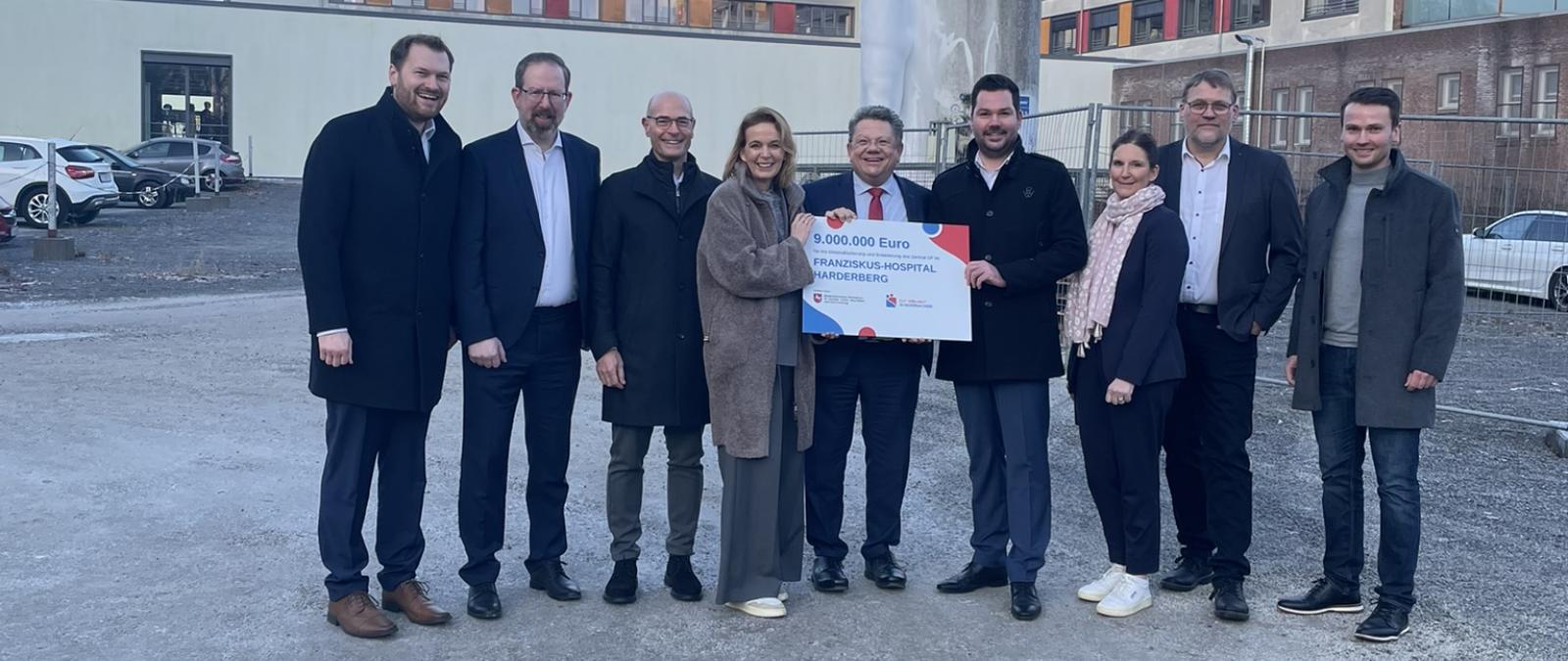 Eine Personengruppe steht vor einem mehrstöckigen Gebäude.