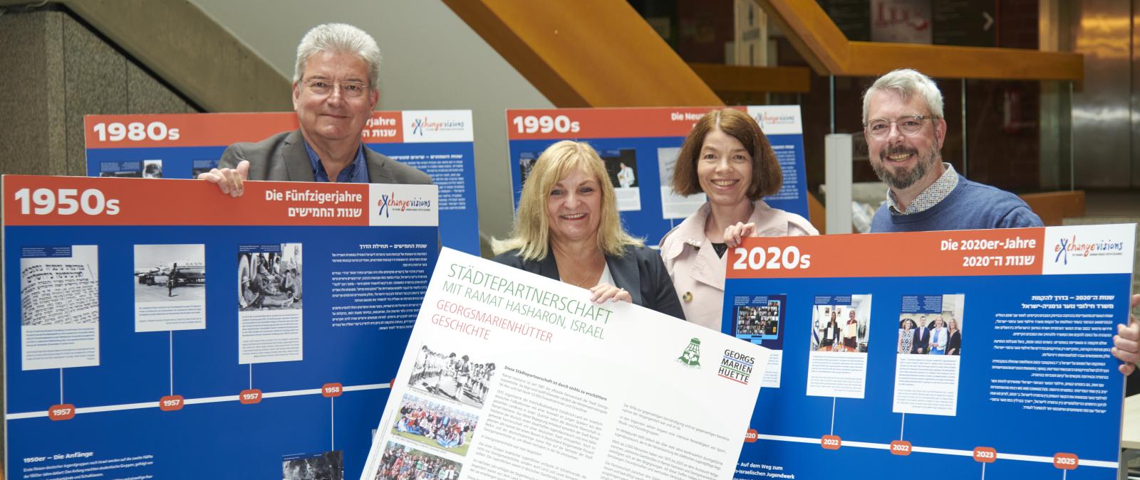 Vier Personen stehen zwischen Ausstellungstafeln