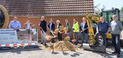 Eine Peronengruppe mit Schaufeln steht hinter einem Sandhaufen.