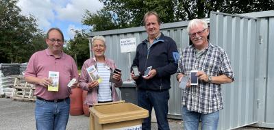 Vier Personen stehen hinter einer Abfalltonne