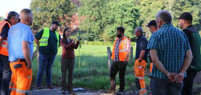 Eine Personengruppe steht am Rand einer Wiese.