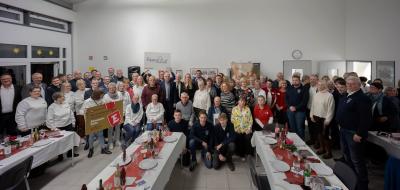 Eine große Personengruppe steht in einem Saal.