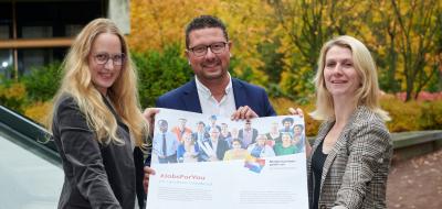 Drei Personen präsentieren ein Plakat.