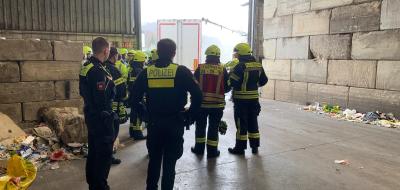 Eine Personengruppe in Uniformen steht in einer Lagerhalle.