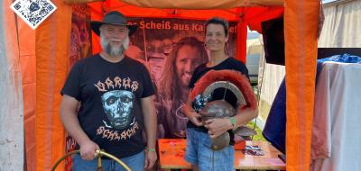 Zwei Personen stehen vor einem orangefarbenen Pavillon.