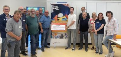 Eine Personengruppe steht links und rechts neben einem Rollup-Poster
