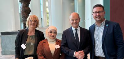 Vier Personen stehen im Foyer eines Gebäudes.