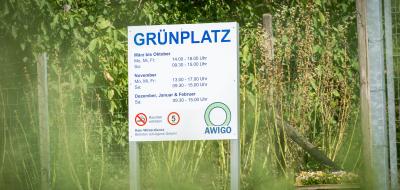 Schild an einem Zaun mit Grünzeug dahinter