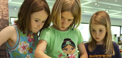 Drei Kinder stehen an einer Station in einer Ausstellung