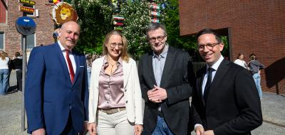 Vier Personen stehen vor einem Backsteingebäude.