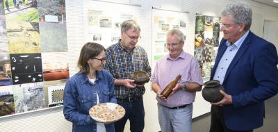 Vier Personen stehen vor einer Wand mit Postern.