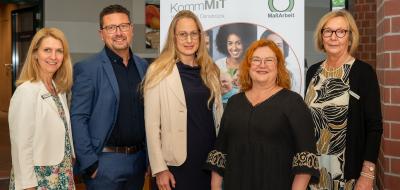 5 Personen vor Plakat