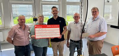 Fünf Personen präsentieren ein symbolischen Spendenscheck