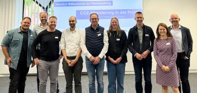 Eine Personengruppe steht vor einer Projektionsfläche.