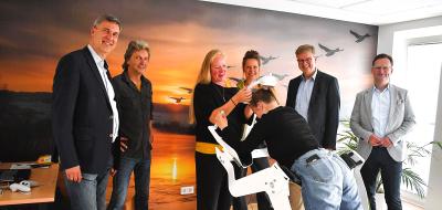 Eine Personengruppe steht in einem Raum vor einem Flugsimulator.