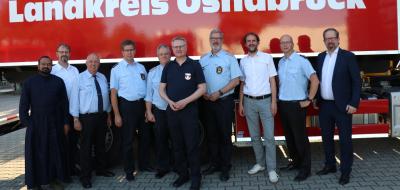 Eine Personengruppe steht vor einem Feuerwehrfahrzeug