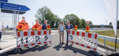 Fünf Personen öffnen einen Straßenbauabsperrung.
