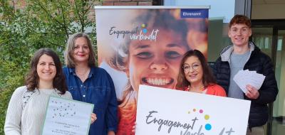 Vier Personen stehen neben einem Rollup-Poster.