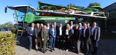 Eine Personengruppe steht vor einer Landmaschine.