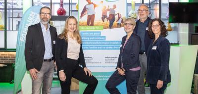 Fünf Personen stehen neben einem Rollup-Poster.