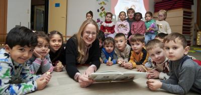 Eine Personengruppe liegt auf dem Boden eines Raumes und schaut in die Kamera.