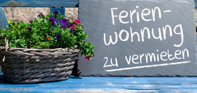 Schild steht auf einer Bank mit der Aufschrift Ferienwohnung zu vermieten.