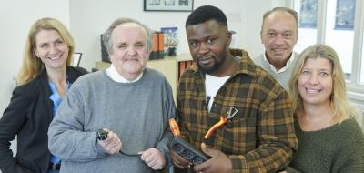 Fünf Personen mit Steckerleiste in den Händen stehen in einem Büro.