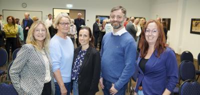 Fünf Personen stehen nebeneinander in einem Raum.